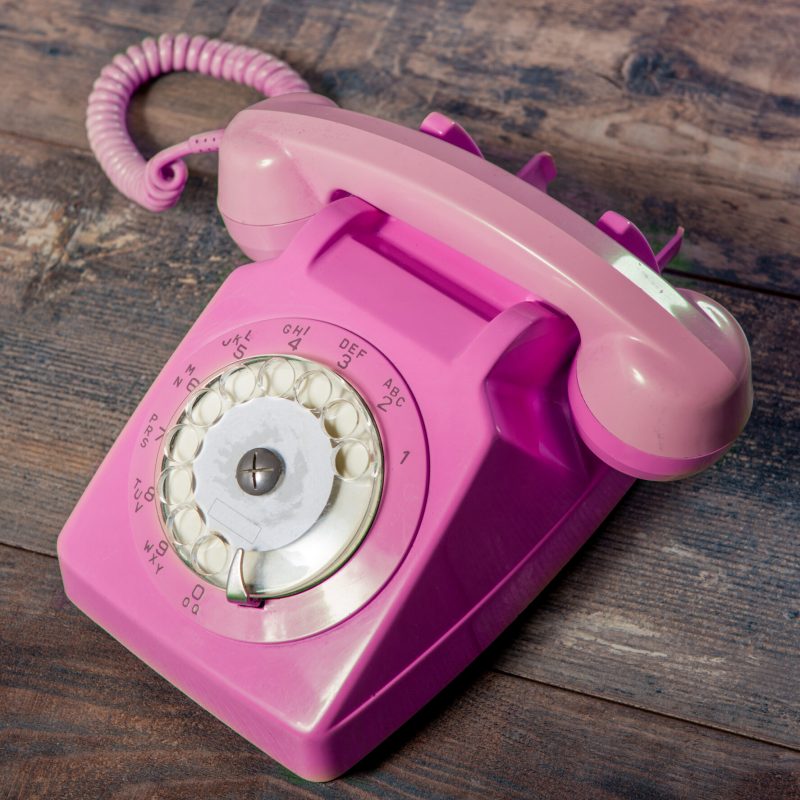 Retro pink rotary telephone on wood table